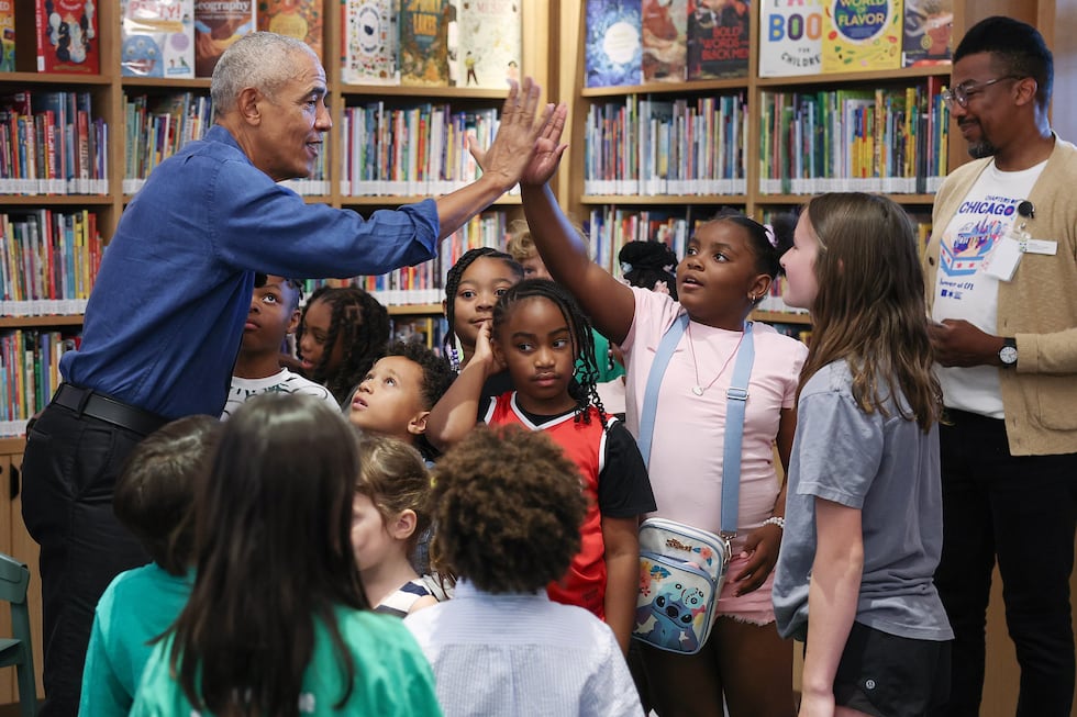 Former President Barack Obama gives a high-five during a book reading with children on opening...