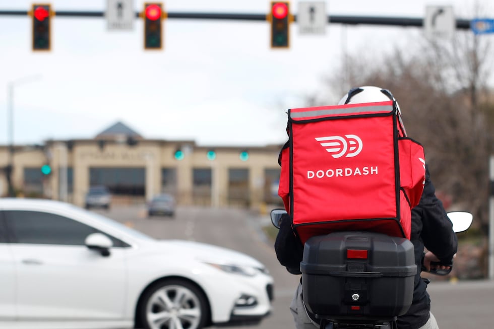 FILE - A food delivery motorcycle rider waits for the traffic light to change March 30, 2020,...