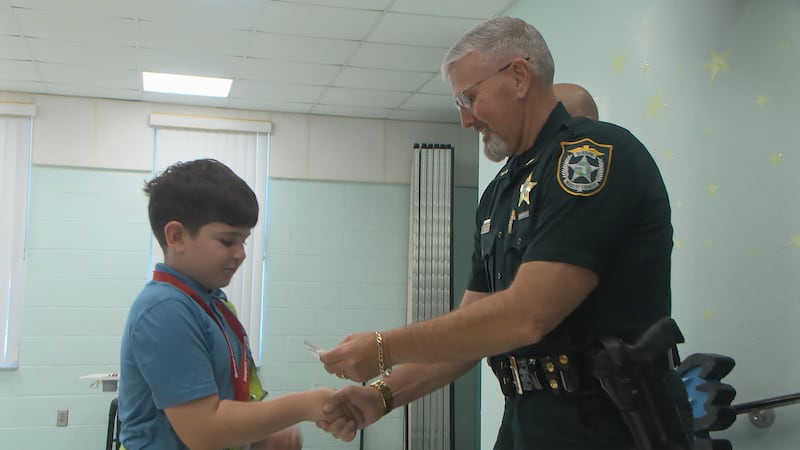 Sheriff Rick Wells shakes hands with each Safety Patrol 5th grader at Rowlett Elementary...