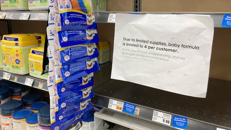 A sign telling consumers of limits on the purchase of baby formula hangs on the edge of an...
