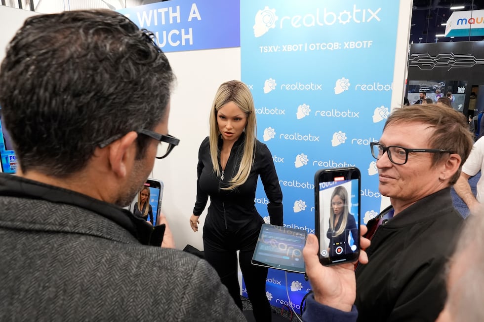 FILE - A Realbotix humanoid robot, center, speaks with attendees at a Realbotix booth during...